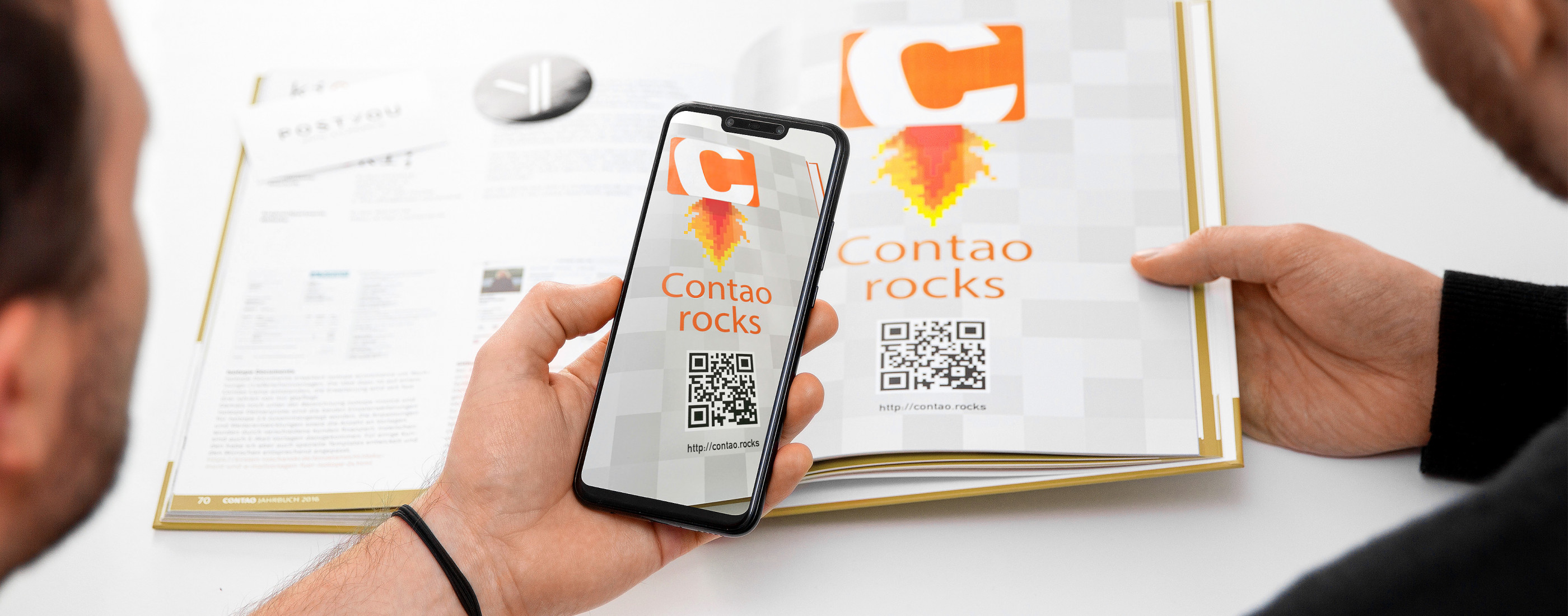Aus dem Contao-Jahrbuch wird mit einem Smartphone von der Seite "Contao-Rocks" der QR-Code abgescannt